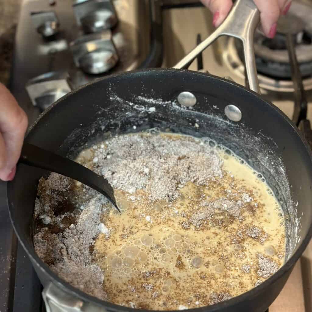 Whisking together the ingredients for the filling of a butterscotch pie in a saucepan.