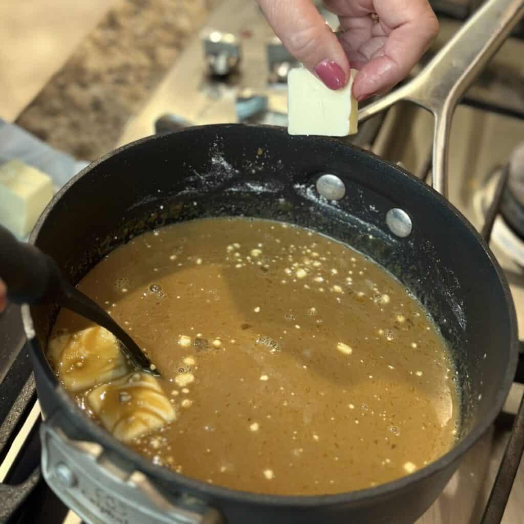 Whisking together the ingredients for the filling of a butterscotch pie in a saucepan.