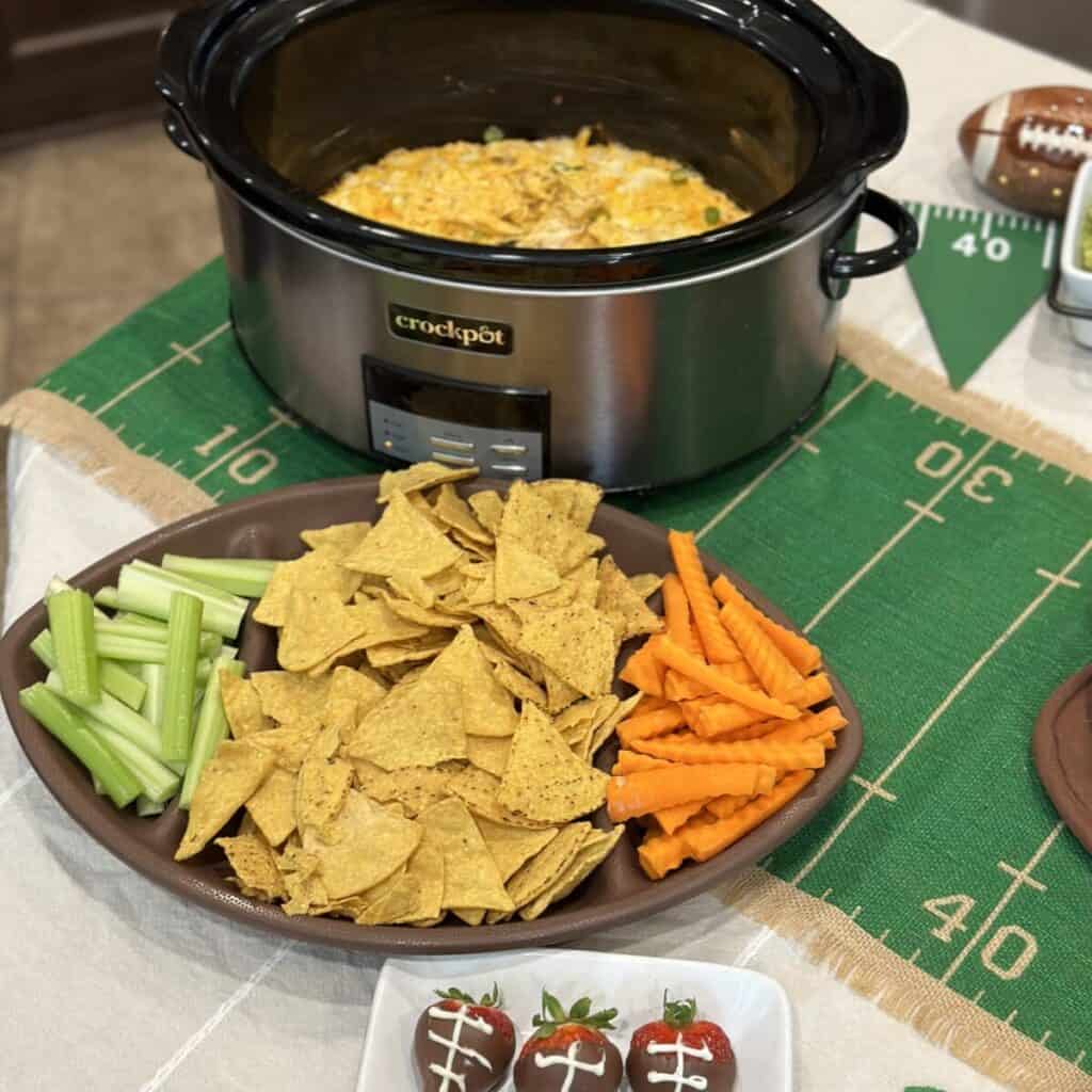 A football plate with carrots celery and chips for dipping in buffalo chicken dip.