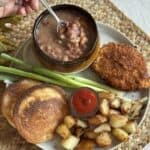 A plate with soup beans, hoecakes, fried potatoes and a fried pork chop.