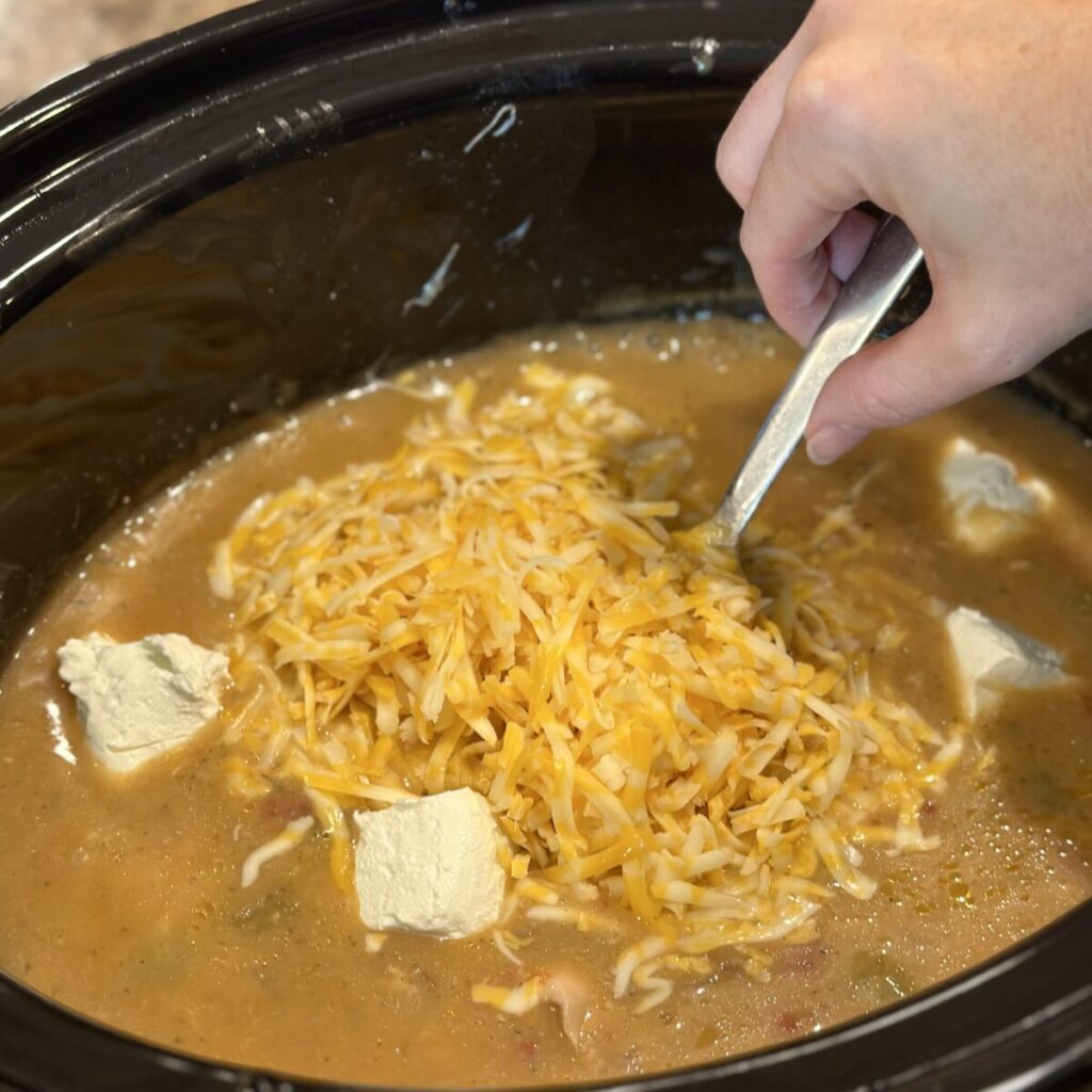 Adding cheese to a sauce in a crock pot.