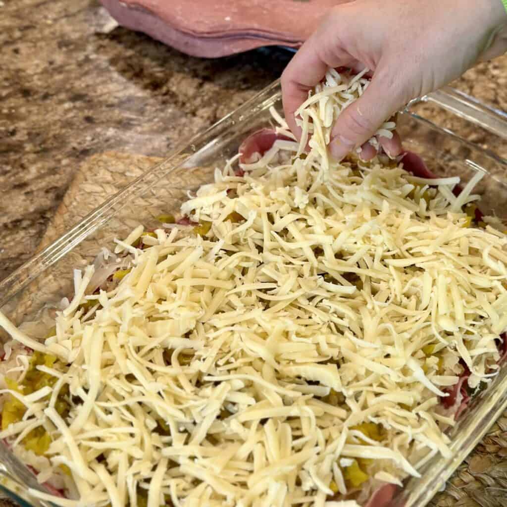 Adding swiss cheese tot the top of Reuben casserole.