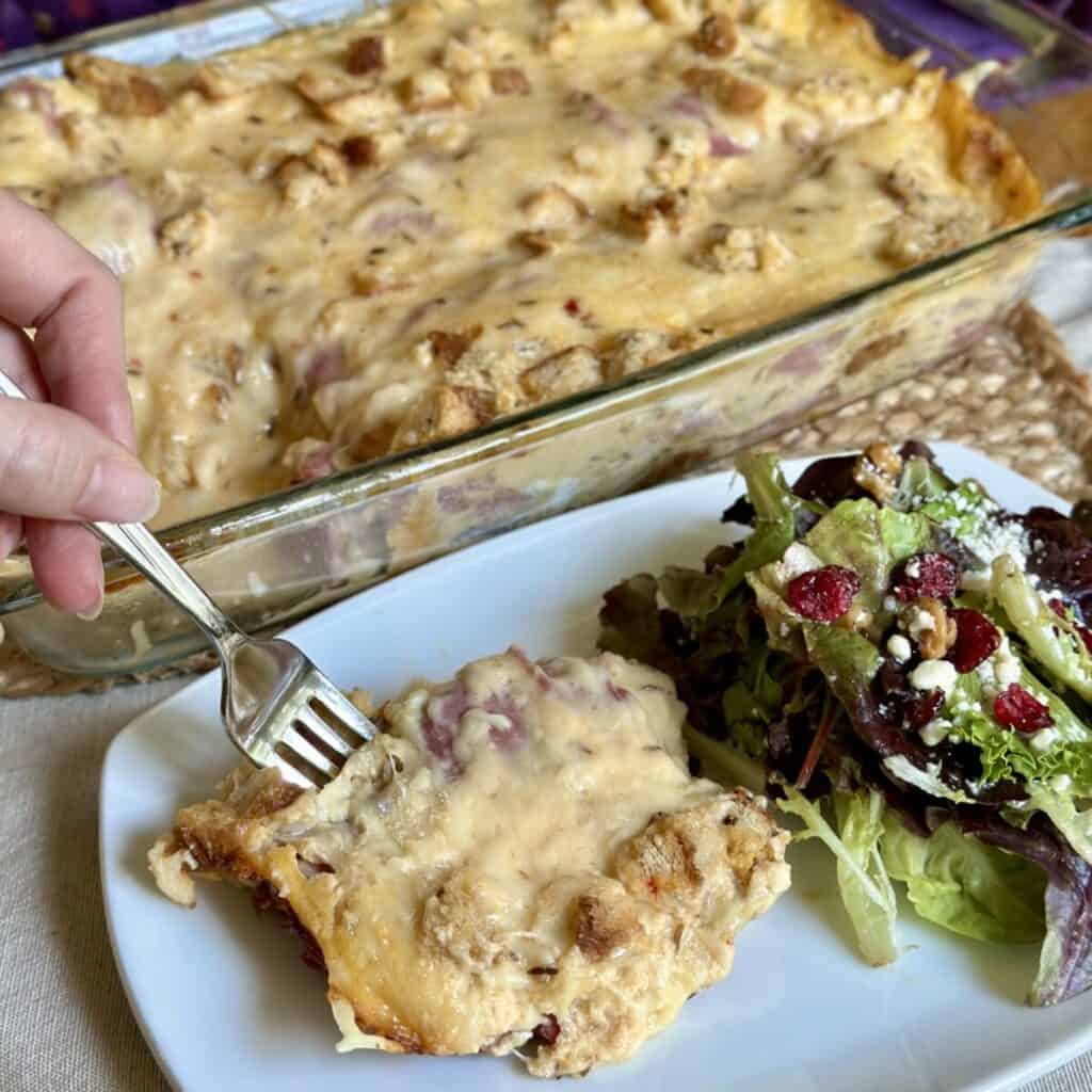 A plate with a slice of Reuben casserole and a salad.