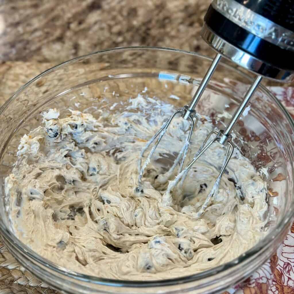 A bowl of whipped cream cheese spread with cranberries.