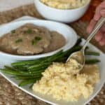 A plate with cheesy rice, green beans and hamburger steak.