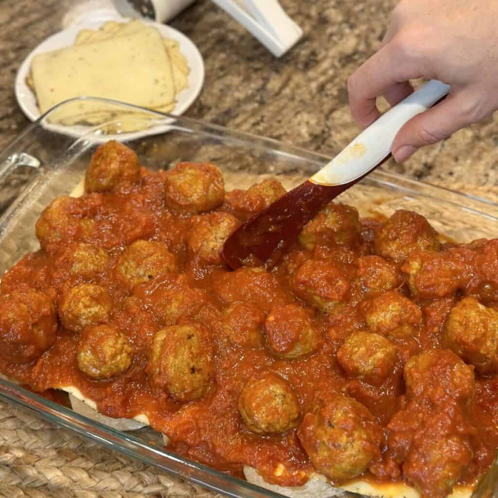 Adding the meatball layer to meatball casserole.