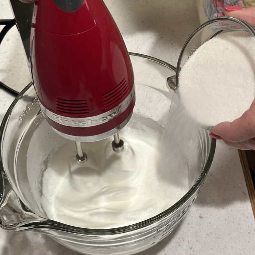 Adding sugar to egg whites.