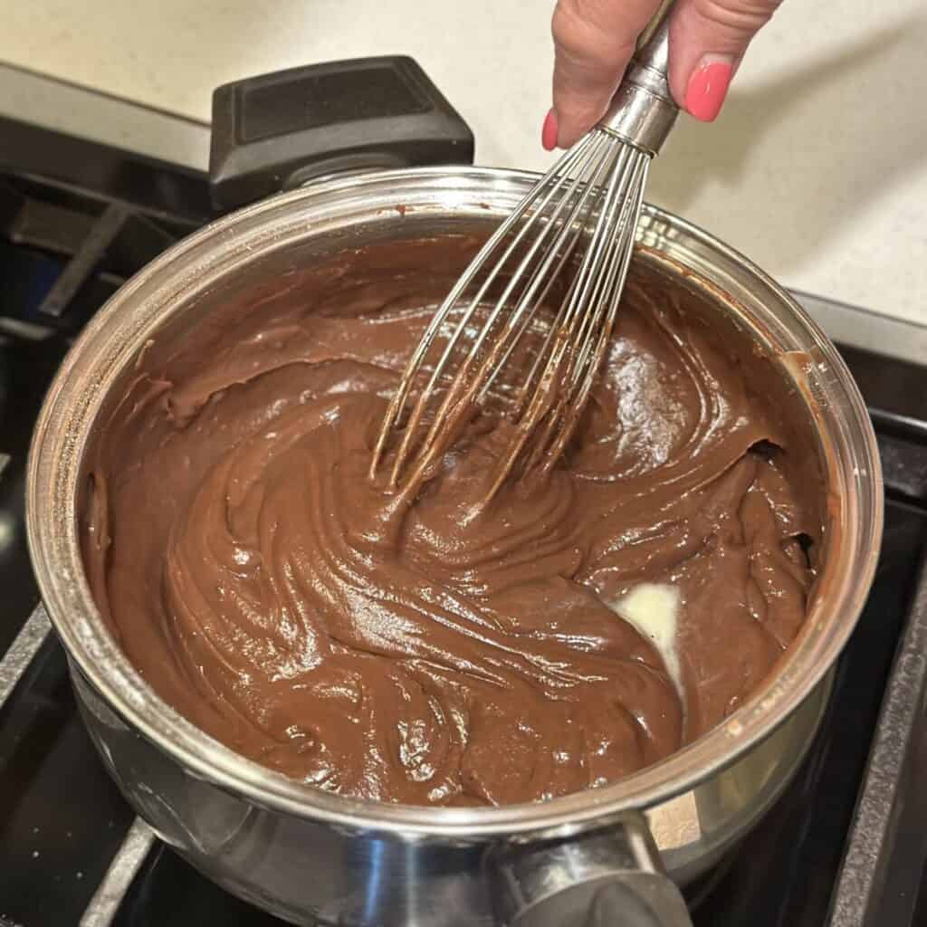 Making the filling for a chocolate meringue pie in a pan.