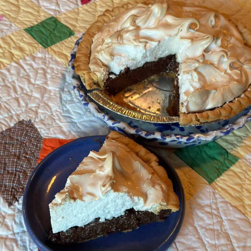 A chocolate meringue pie and a slice on a plate.