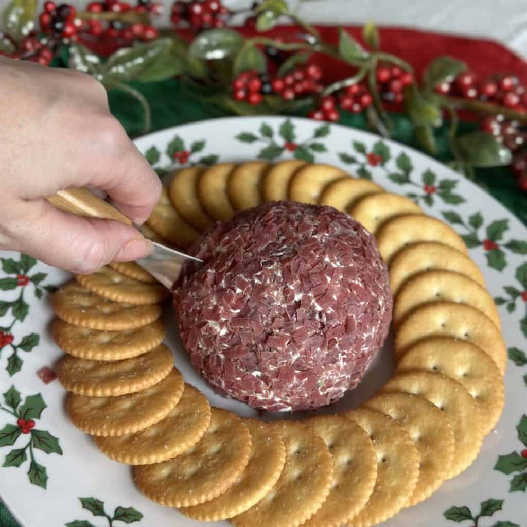 A cheeseball on a plate with crackers.