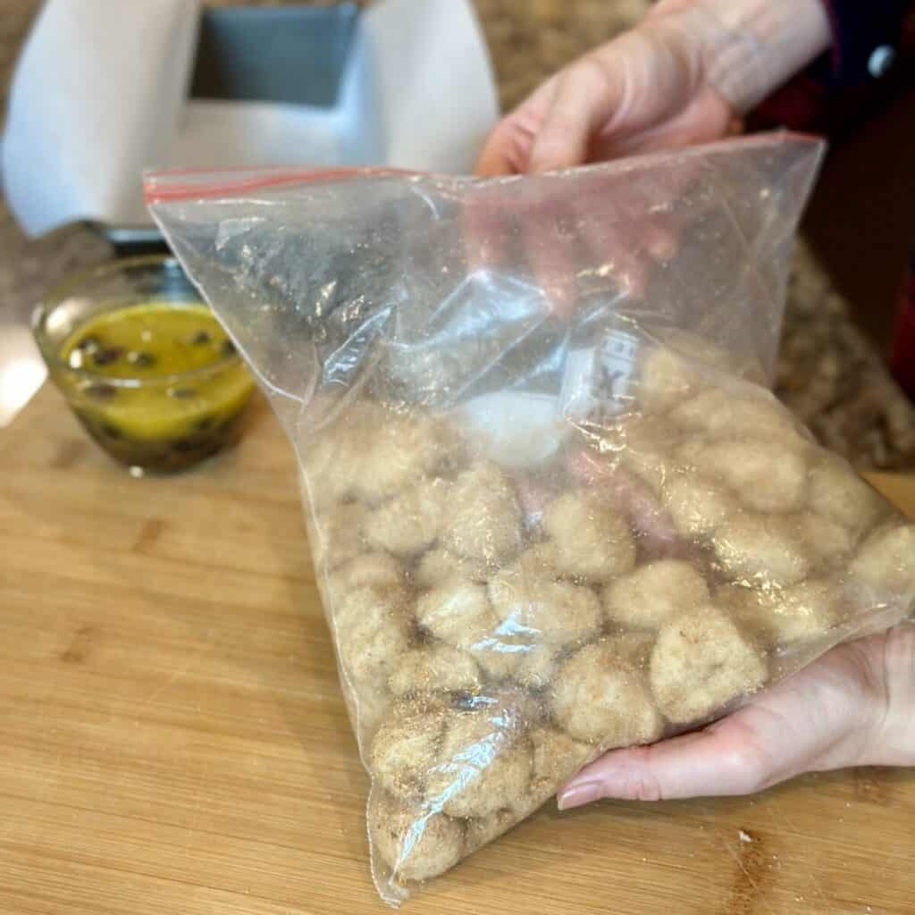 Coating biscuit dough with cinnamon sugar in a bag.