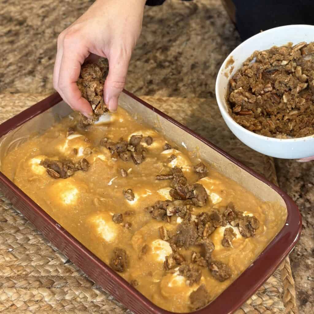 Sprinkling the streusel on top of sweet potatoes,