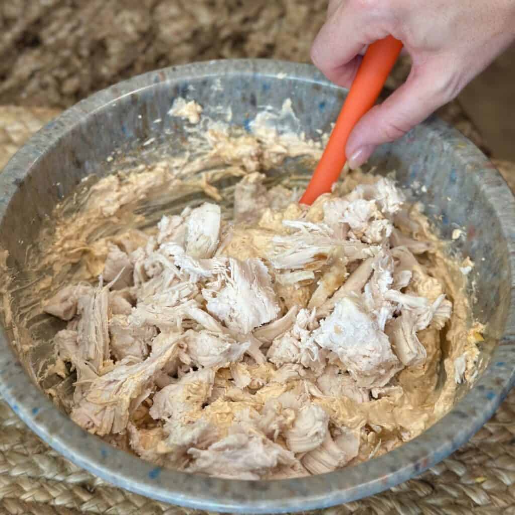 Adding chicken to Nashville hot chicken dip.