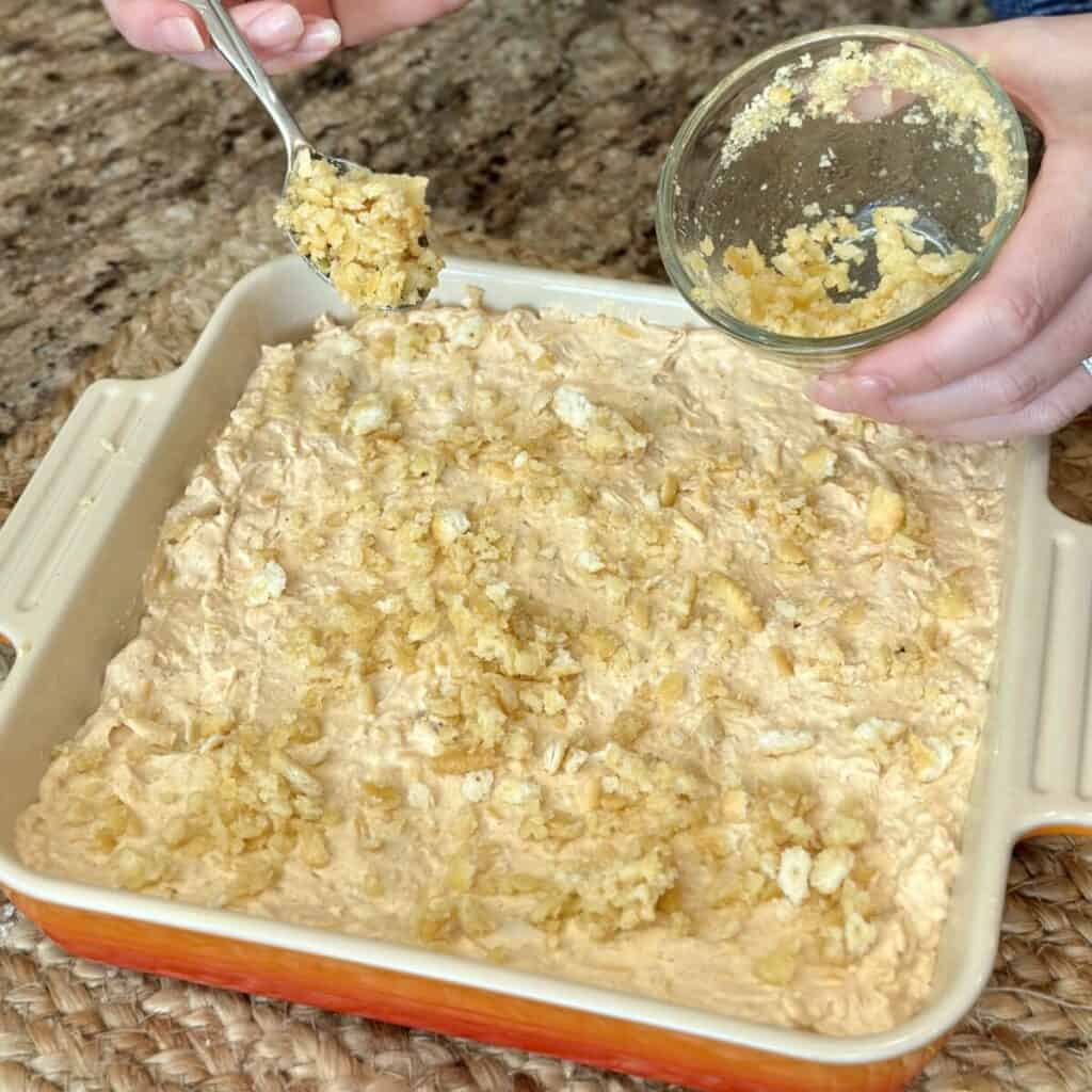 Adding a crunchy cracker topping to the top of a Nashville hot chicken dip.