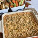 A baking dish of Nashville hot chicken dip and veggies and pretzels for dipping.