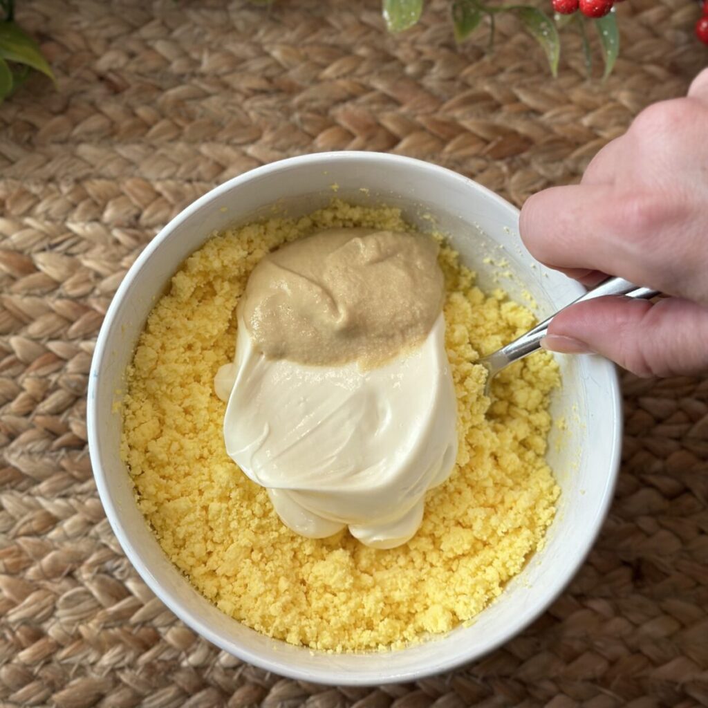 Making the filling for deviled eggs in a bowl.