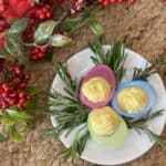 Colored deviled eggs on a saucer.