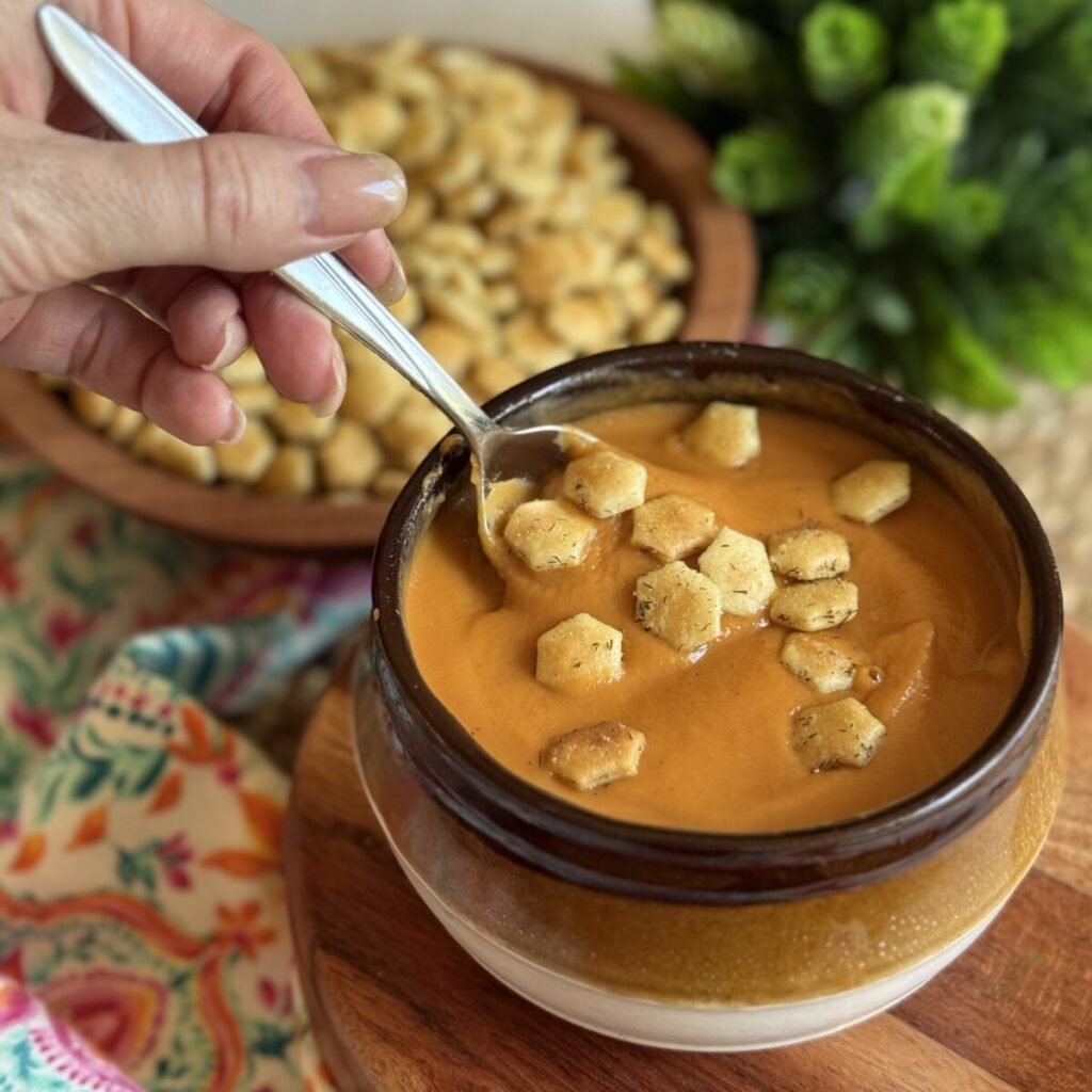 A bowl of soup with crackers on top.