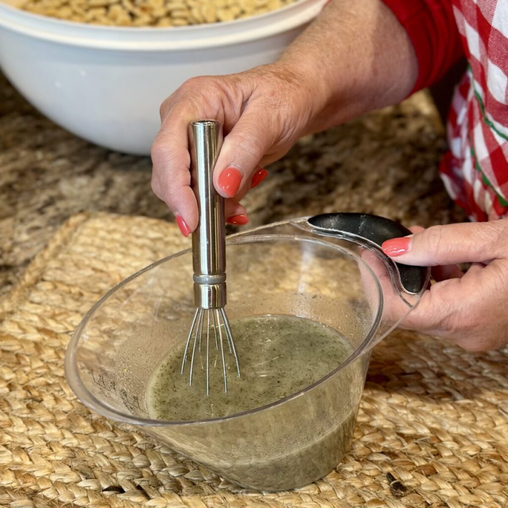 The seasoned oil blends in a measuring cup for ranch dill oyster crackers.